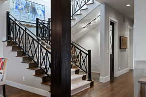 Staircase featuring decorative black metal railings, wood-finish treads, and carpeted risers