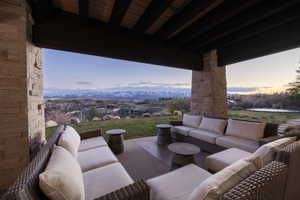 Expansive covered patio featuring stone-clad pillars, exposed wood ceiling beams, and a concrete floor