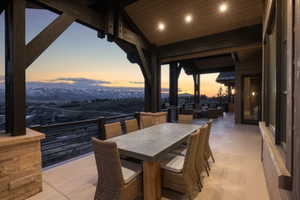 Expansive covered outdoor patio featuring a concrete surface, exposed wood beams, stone pillar accents, and direct mountain scenery