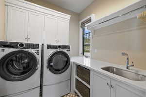 Dedicated laundry room featuring white cabinetry, a built-in sink with chrome faucet, and a countertop workspace