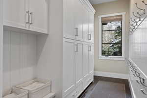 Built-in white cabinetry with polished chrome hardware, dark wood-finish flooring, and a window with natural light