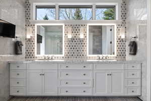 Dual vanity with white cabinetry and integrated sinks set beneath illuminated mirrors