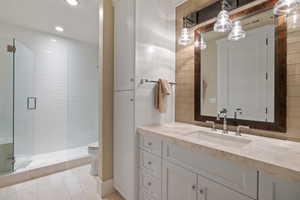 White vanity with stone countertop, undermount sink, and polished chrome faucet