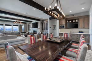 Open-concept living space featuring a substantial wood-finish dining table, exposed ceiling beams, and recessed lighting
