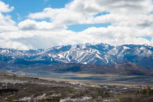 Snow-capped mountains with visible ski trails and a distant residential area
