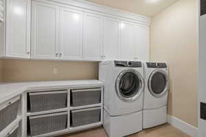 Laundry room featuring extensive white shaker cabinetry, light-toned countertops, and built-in storage with woven baskets