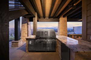 Outdoor kitchen featuring a built-in stainless steel grill, stone veneer island with granite-finish countertop, and recessed lighting
