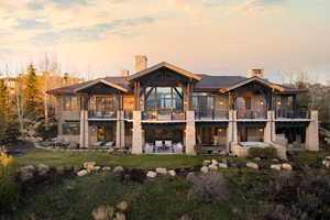 Multi-level residence featuring stone and wood siding, multiple balconies, a lower-level patio, and built-in spa
