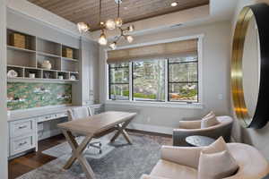 Dedicated office space featuring built-in cabinetry, integrated shelving, and a patterned backsplash