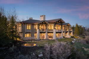 Expansive multi-level residence featuring stone and wood siding, multiple balconies, a lower-level patio, and an in-ground trampoline