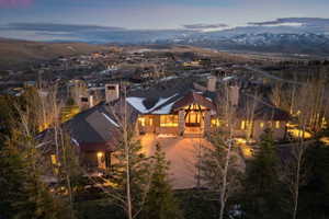 Stone and wood exterior residence featuring multiple prominent chimneys, an arched entry, and a paved driveway