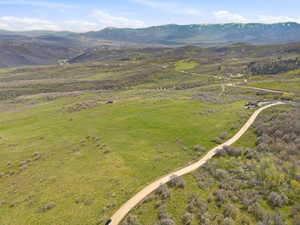 Expansive acreage featuring a winding dirt road, scattered trees, and distant mountain ranges
