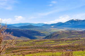Expansive mountain landscape featuring varied elevations and distant snow-capped peaks