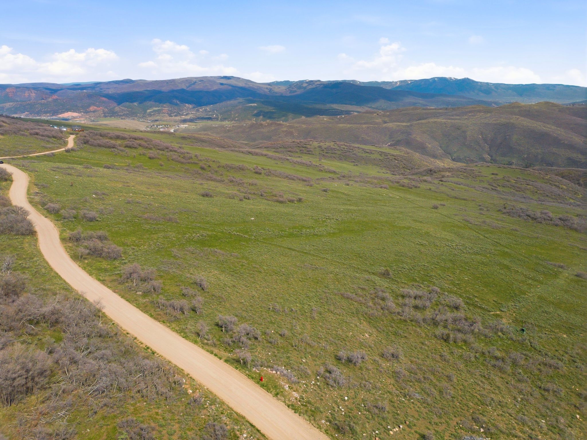 Expansive undeveloped land featuring a winding dirt road and natural vegetation