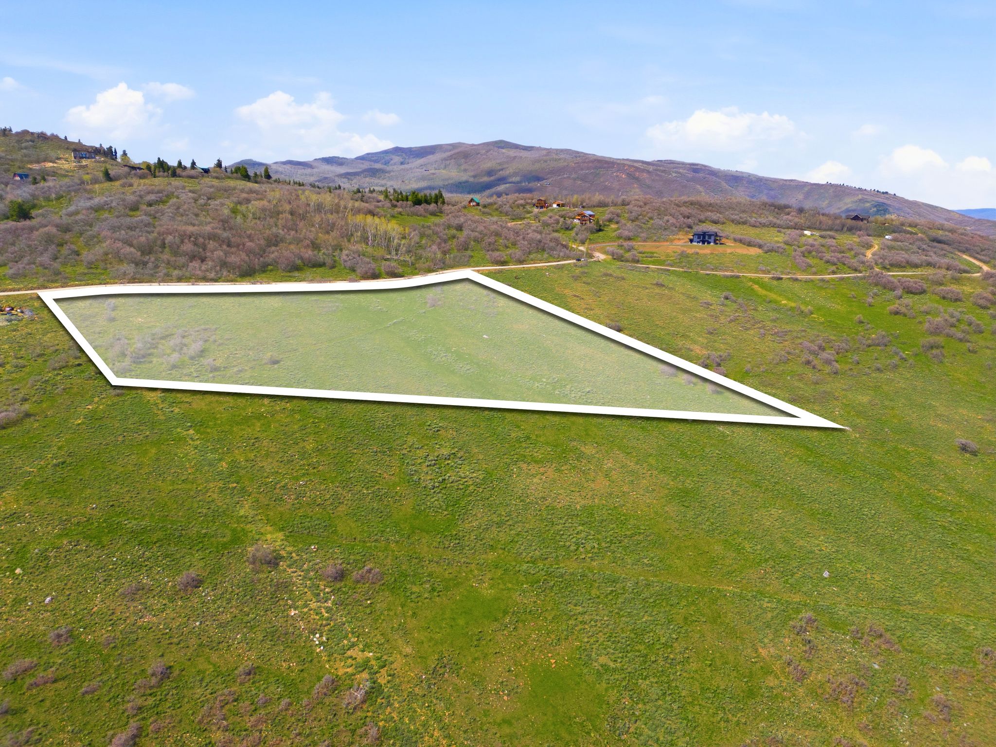 Expansive parcel of land with a rectangular outline, featuring a gentle slope and partial grass coverage