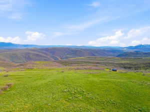 Expansive green acreage featuring distant mountain ranges and a solitary structure