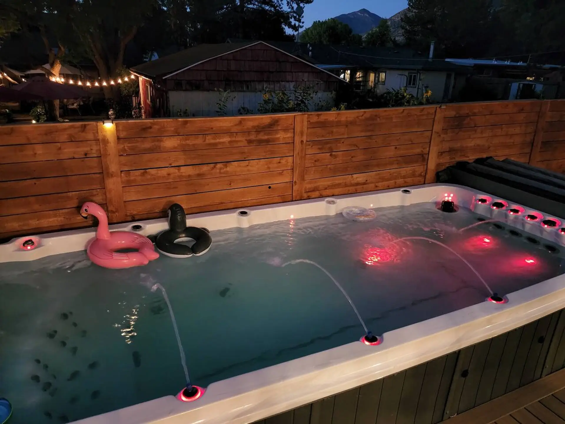 Outdoor swim spa featuring red accent lighting and water jets
