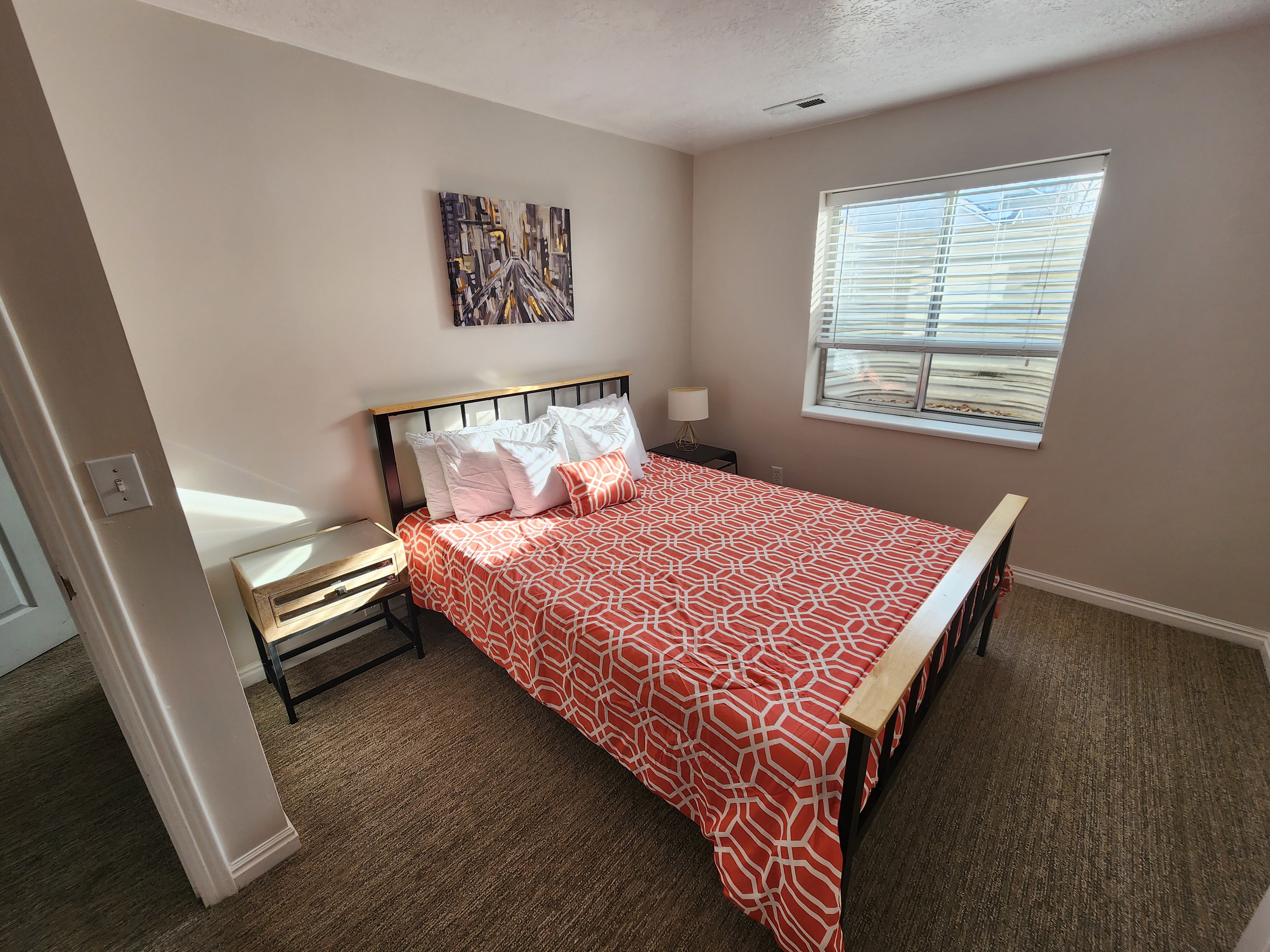 Bedroom featuring neutral wall paint, textured carpeting, baseboard trim, and a window with blinds