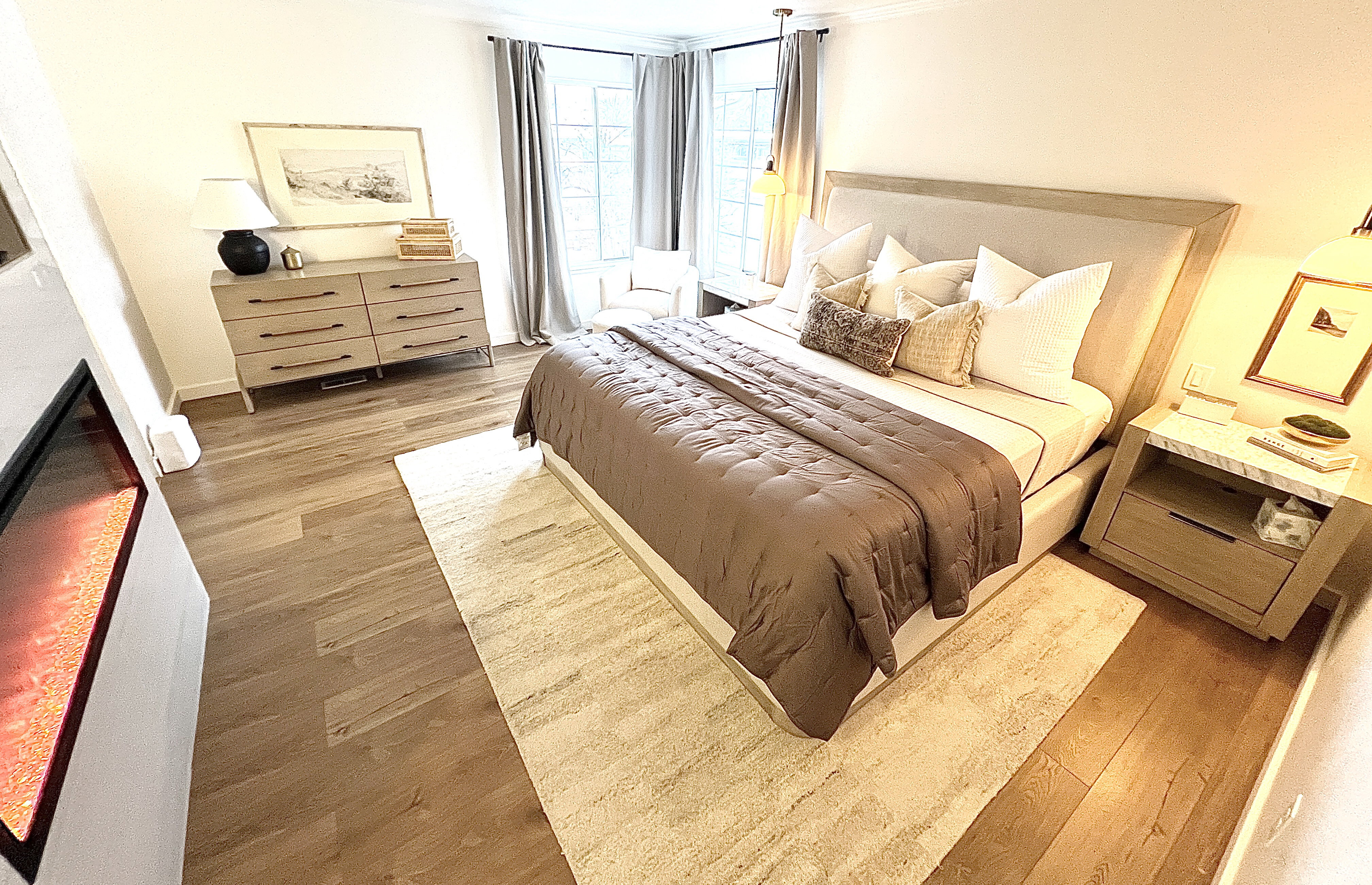 Spacious room featuring wood-finish flooring, a built-in fireplace, and a bay window with drapes
