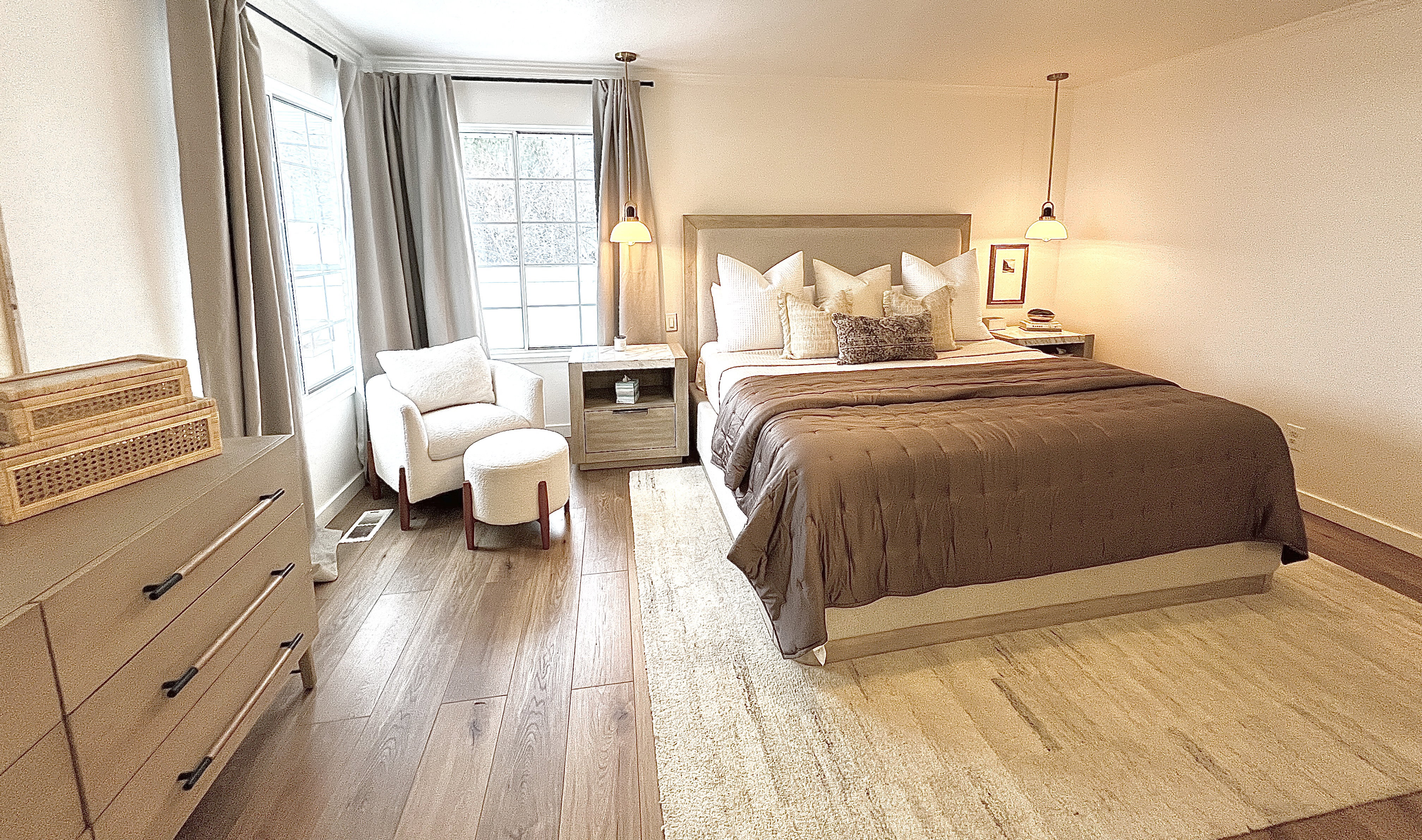 Spacious bedroom with wood-finish flooring, multiple windows, and a neutral color palette