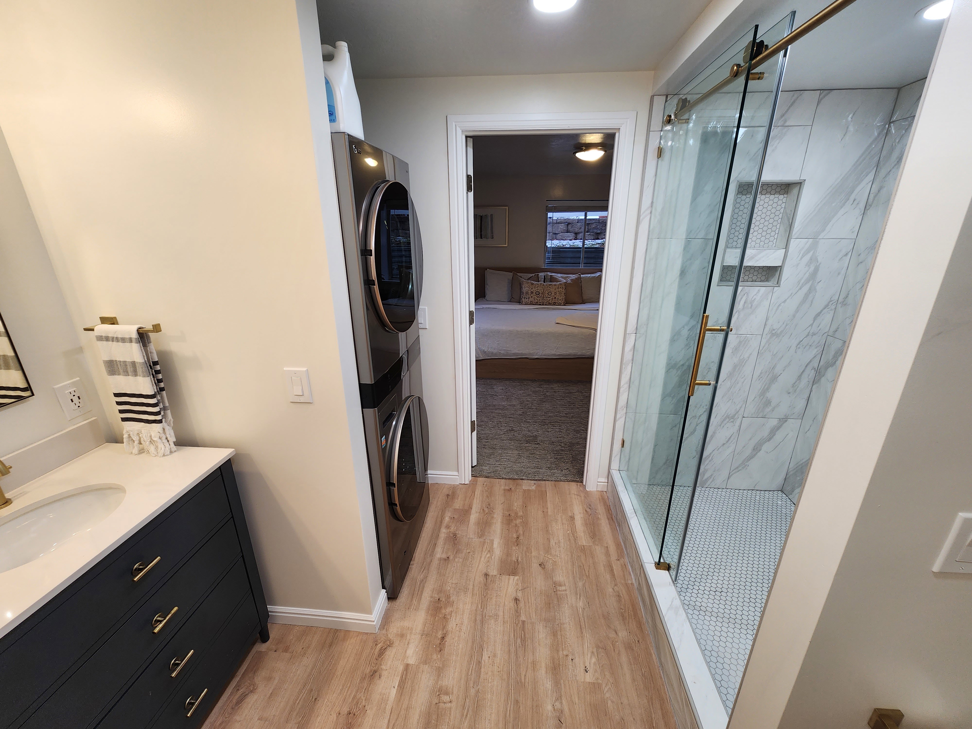 Modern bathroom featuring a glass-enclosed shower with marble-look tile, a built-in shower niche, and a white penny tile floor
