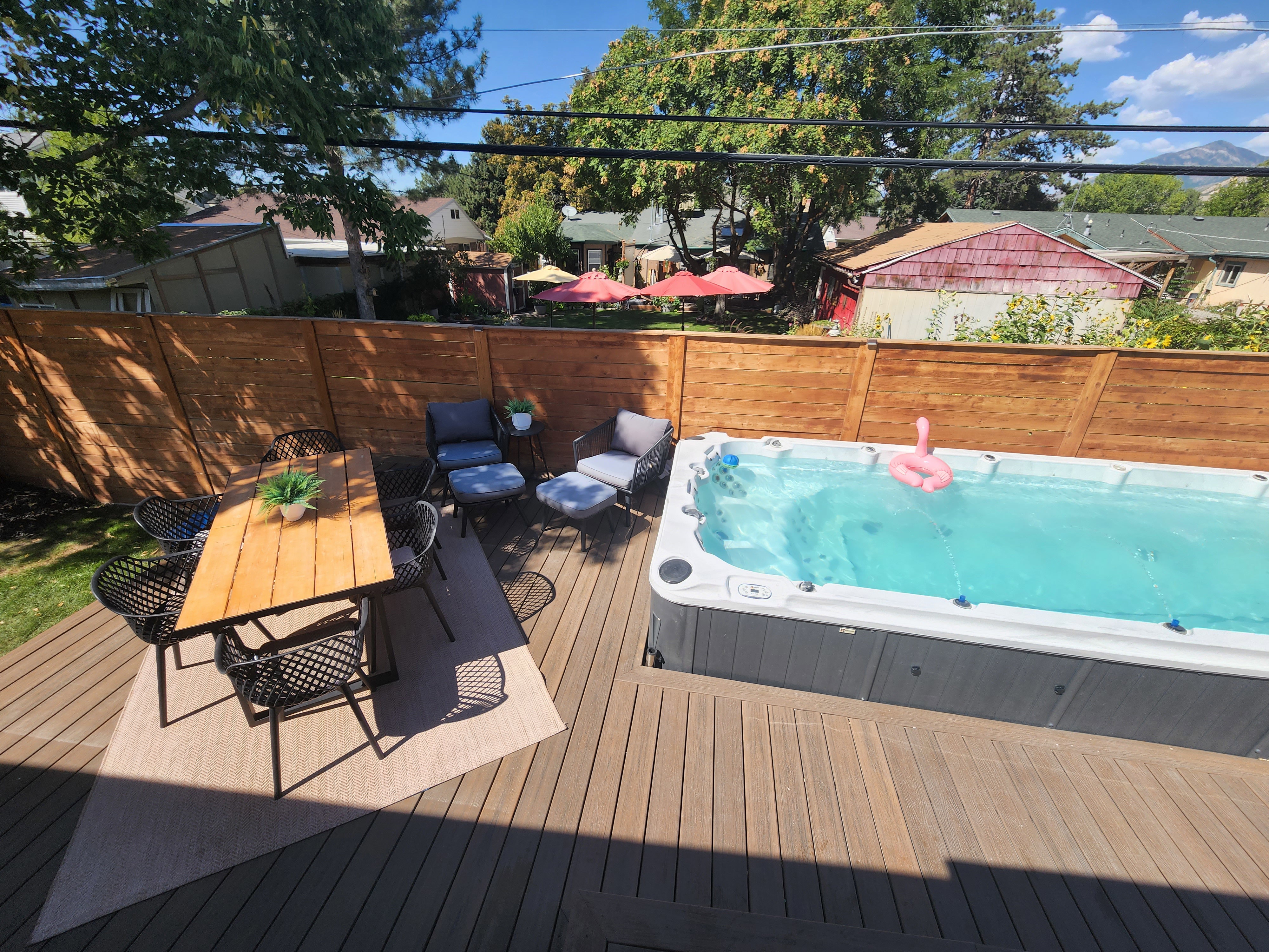 Expansive outdoor living area featuring a large spa, composite decking, and a privacy fence