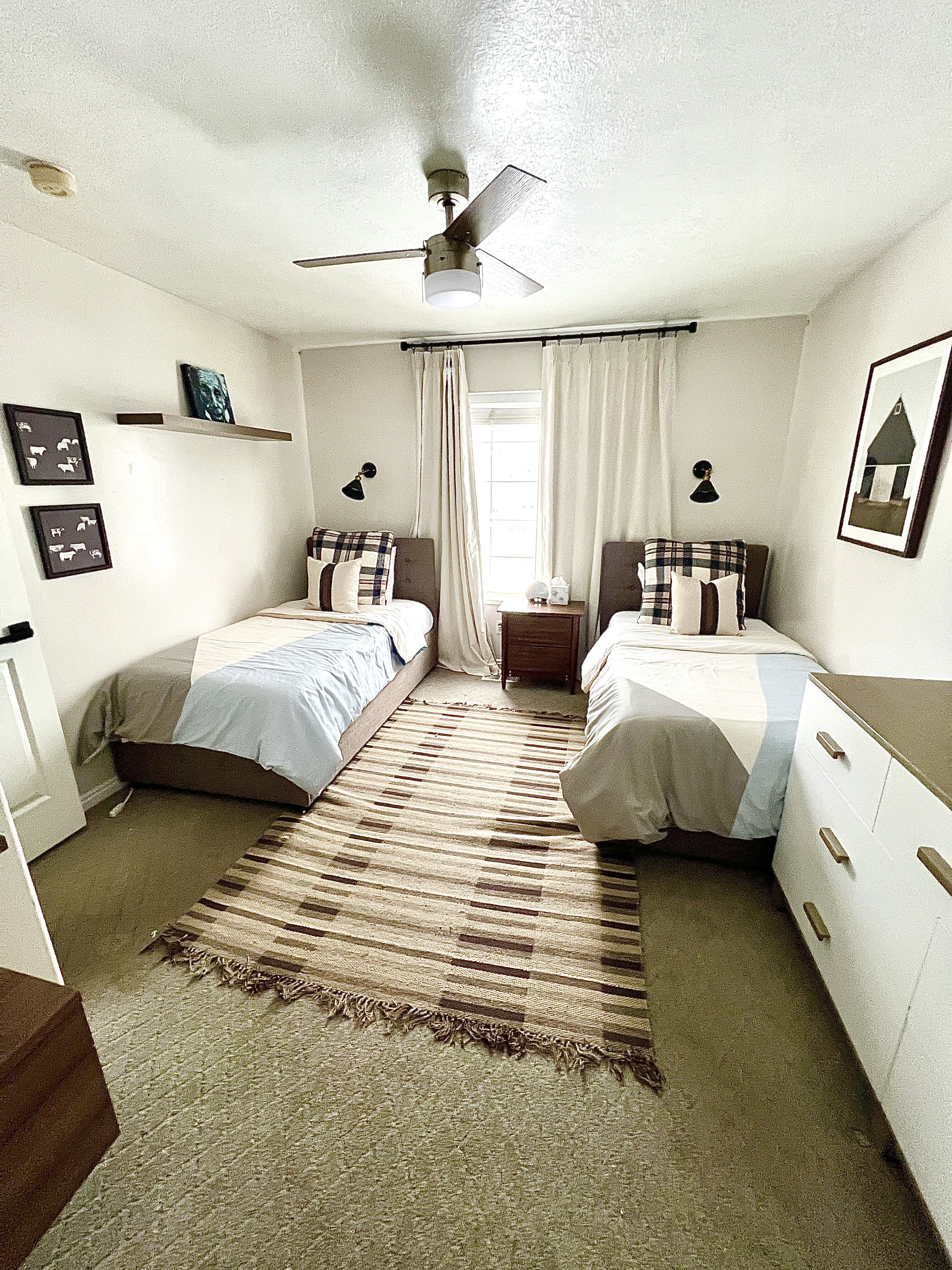 Bedroom with textured carpet, overhead ceiling fan, and window with light-filtering drapes