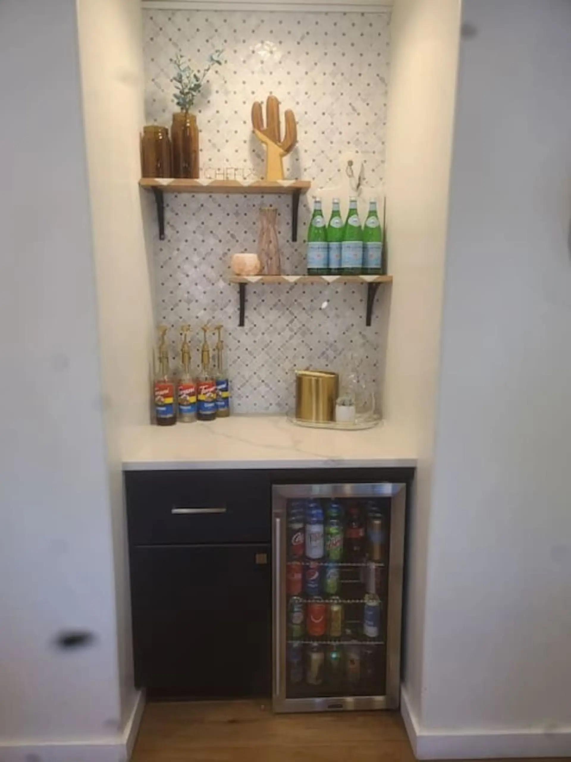 Built-in beverage station featuring a compact refrigerator, a white countertop, and a patterned tile backsplash