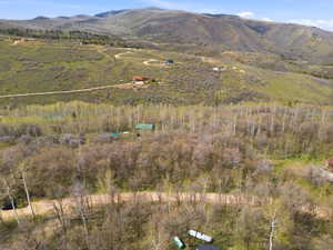Expansive mountainous terrain featuring scattered residential structures, natural foliage, and winding unpaved roads