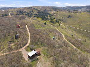 Expansive acreage featuring multiple distinct structures, including a primary residence with a metal roof and an accompanying outbuilding