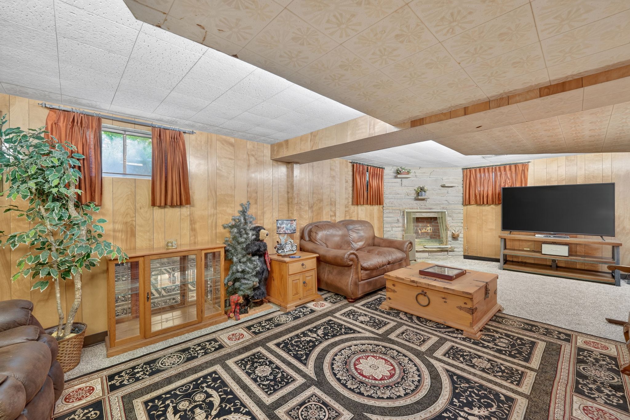 Recreation room featuring wood paneling, a stone fireplace, recessed lighting, and drop ceiling