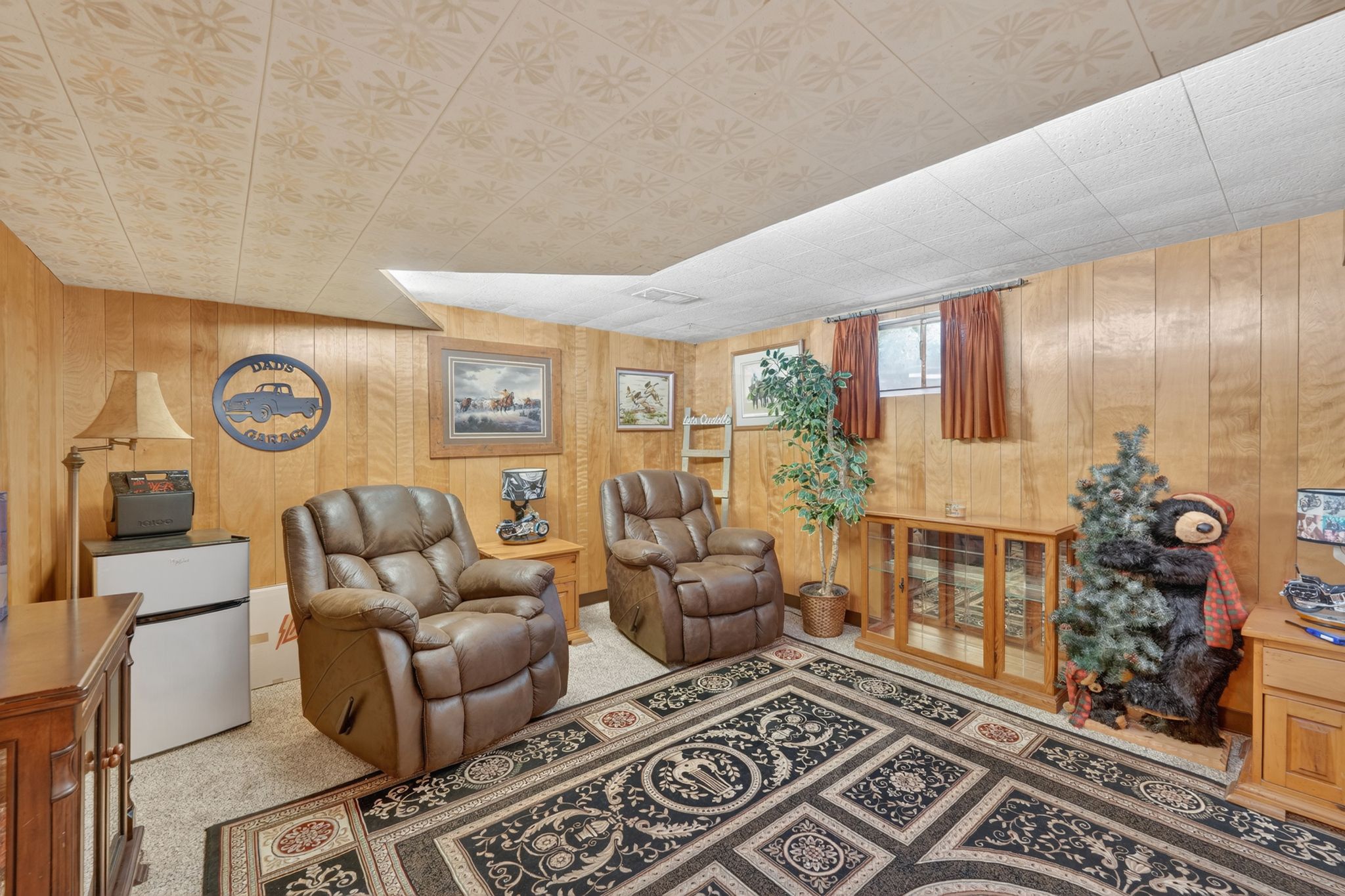 Carpeted recreation room featuring wood paneling, drop ceiling, and recessed lighting
