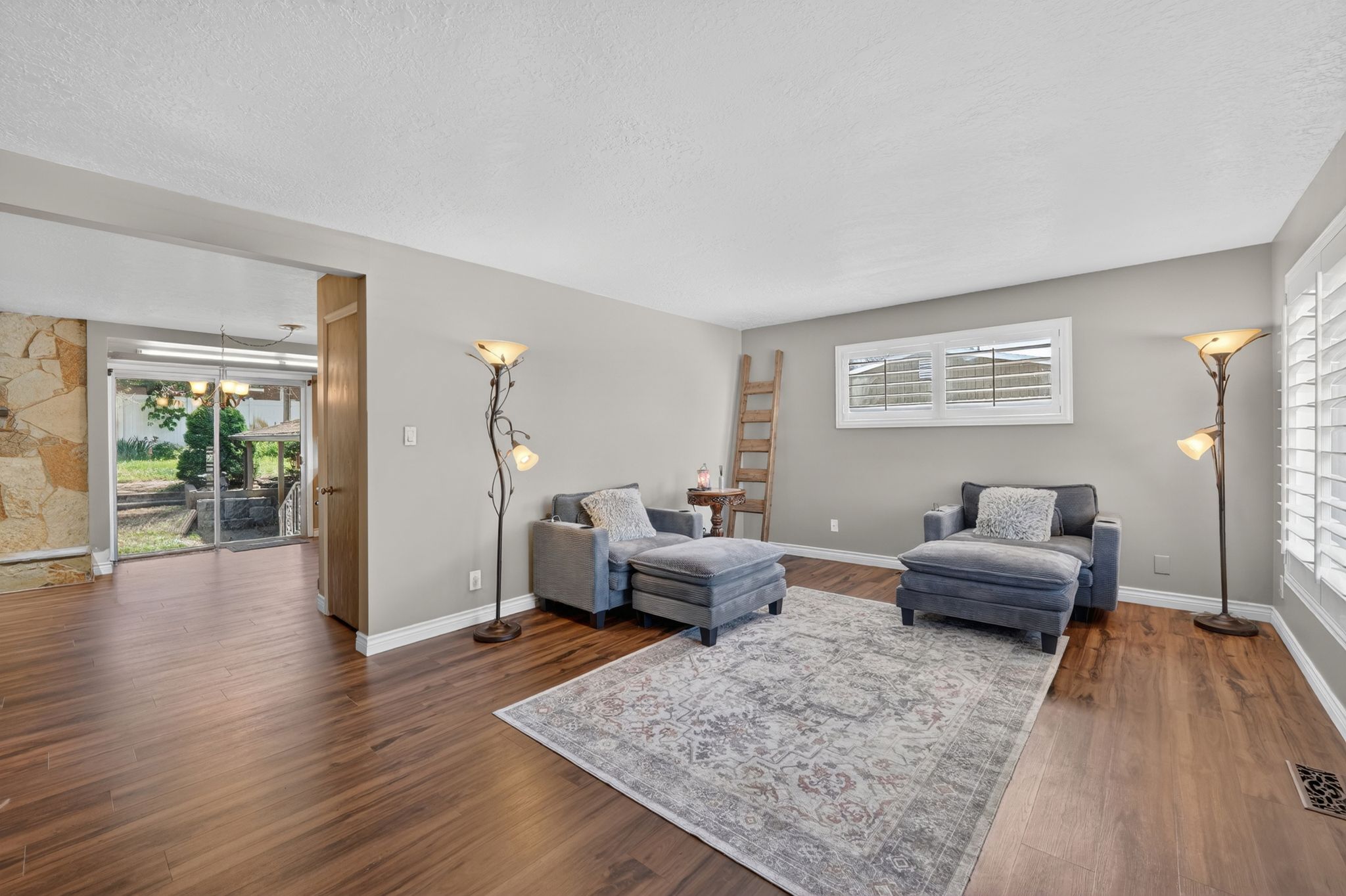 Spacious living area featuring wood-finish flooring, neutral wall paint, and white trim