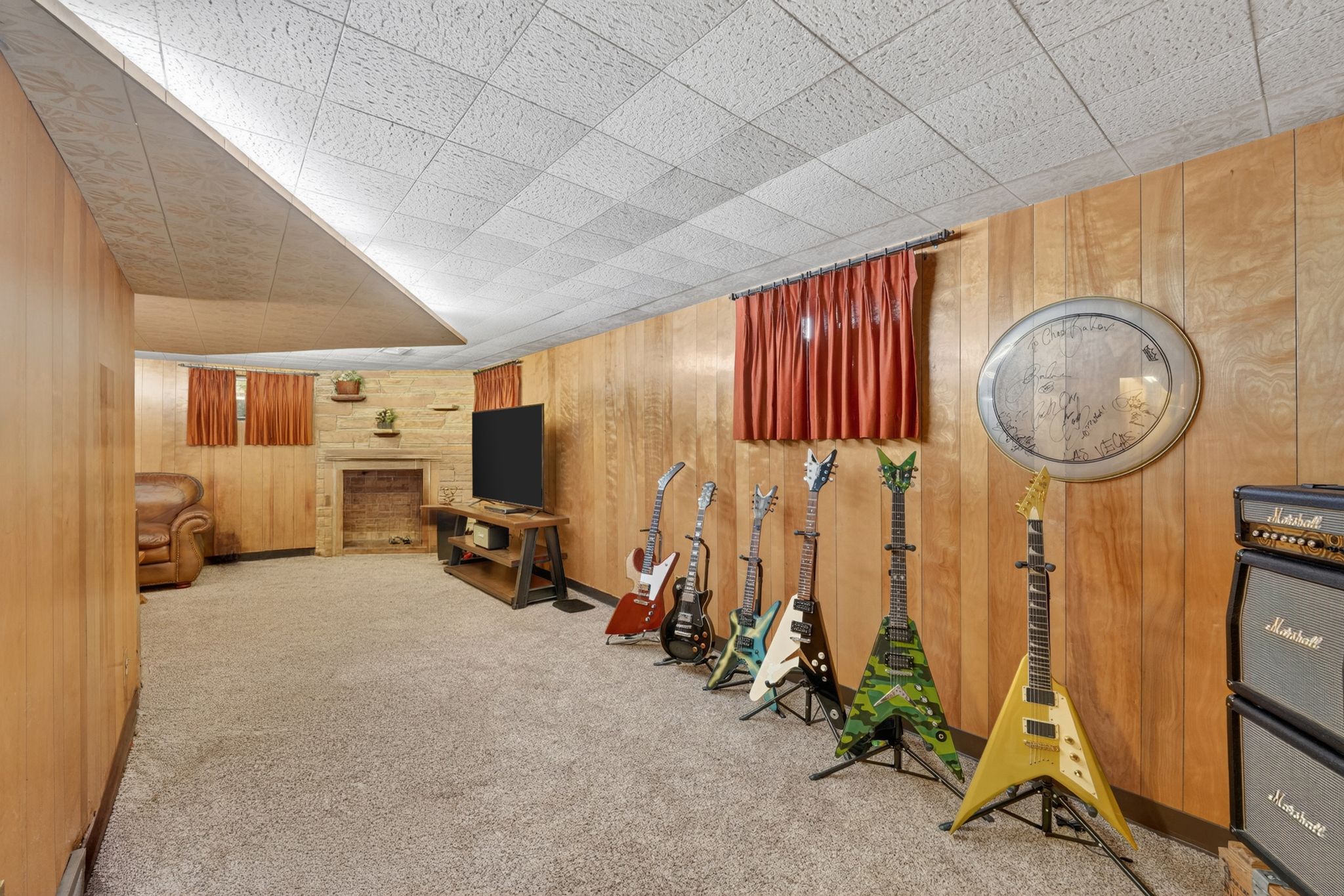 Finished room with light wood paneling, carpeted flooring, and a drop ceiling