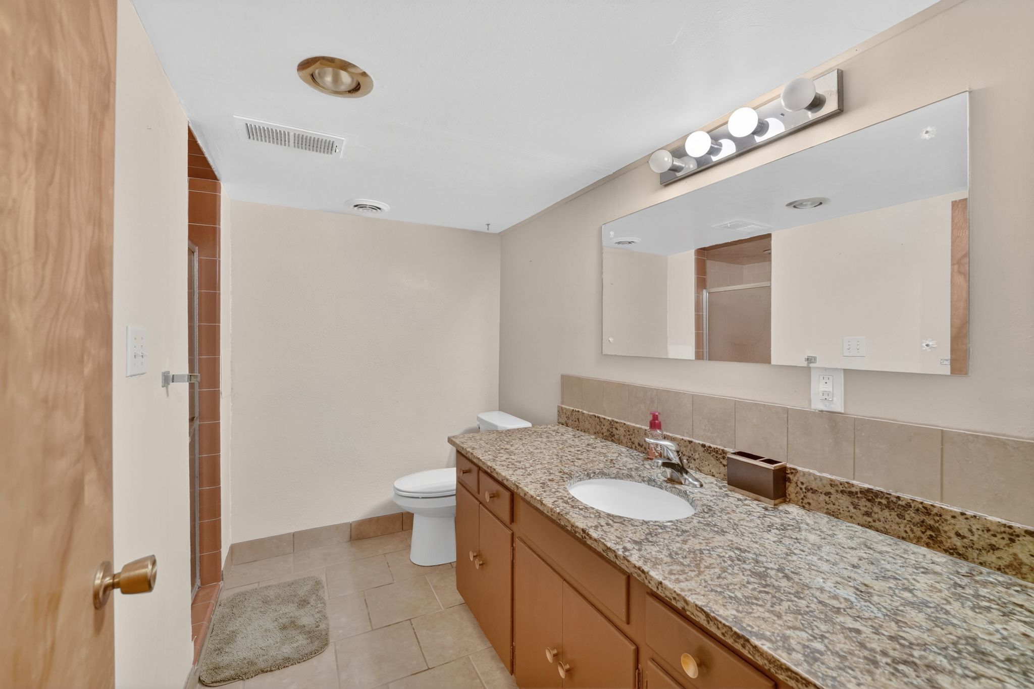 Bathroom vanity with a granite countertop, undermount sink, and wood-finish cabinetry