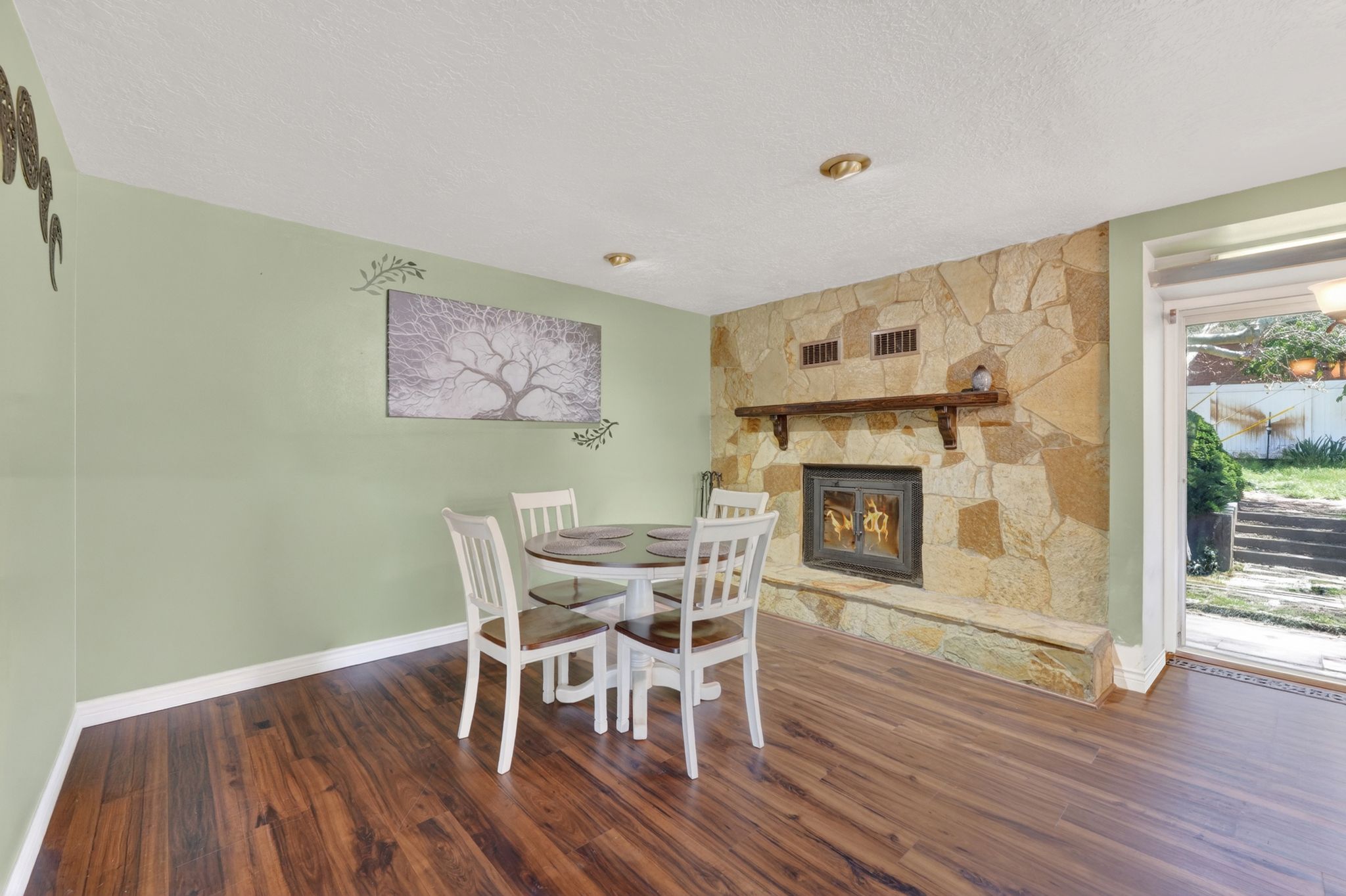 Stone-clad fireplace with a wood mantle, wood-finish flooring, and recessed ceiling lighting