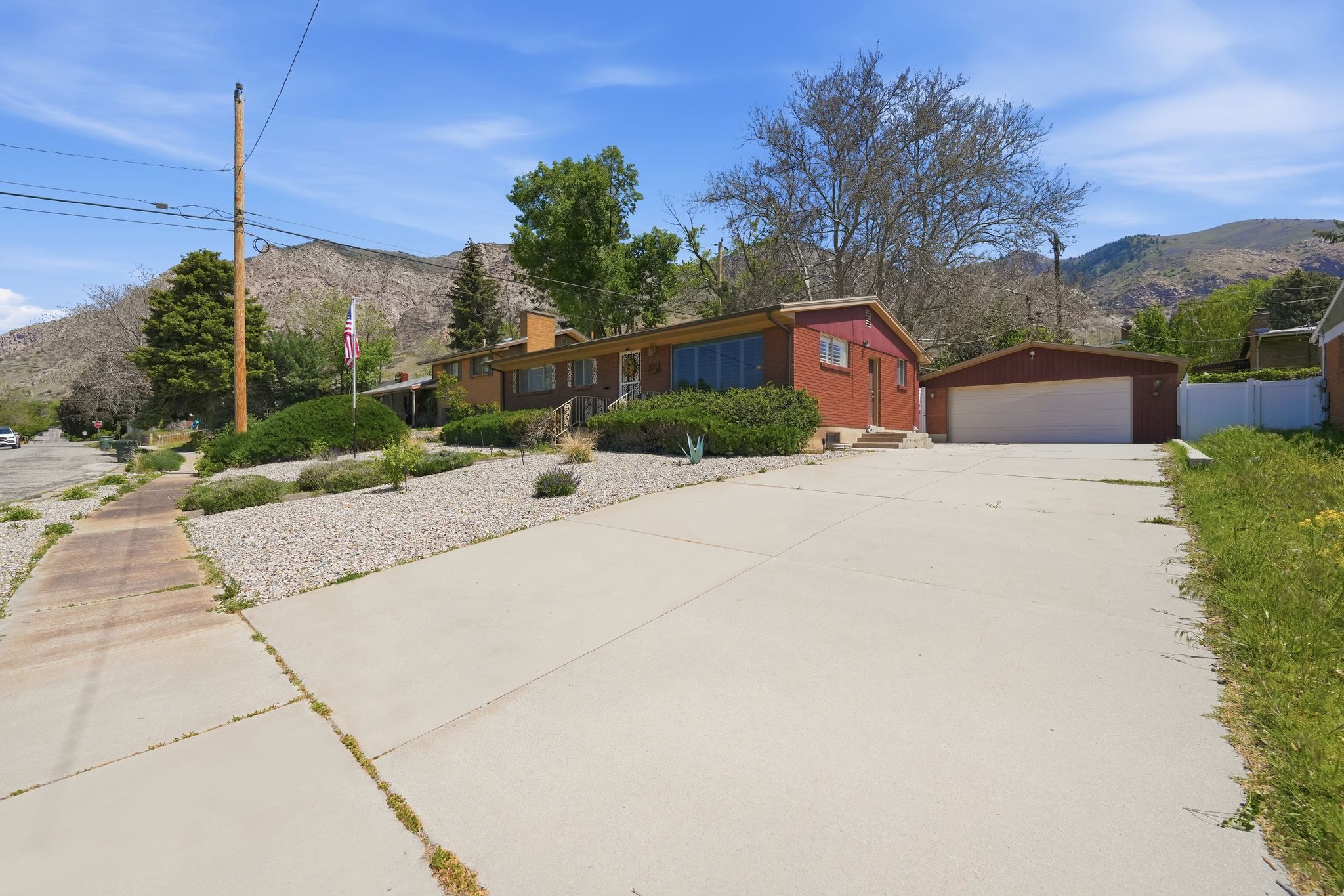 Red brick exterior with a large driveway and separate garage structure