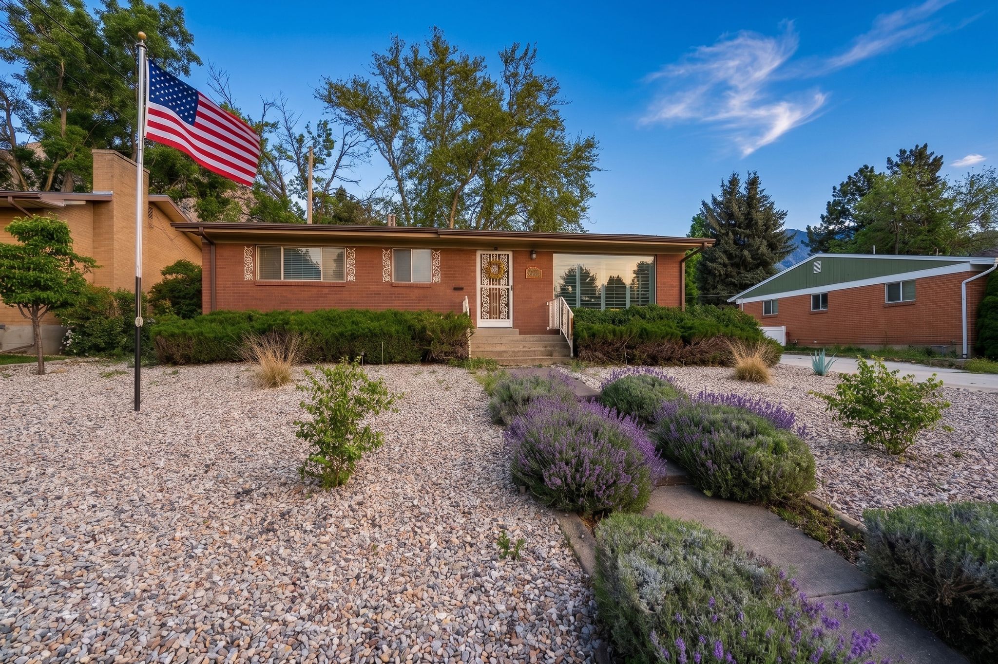 Brick exterior with a prominent front entrance, large picture window, and mature landscaping