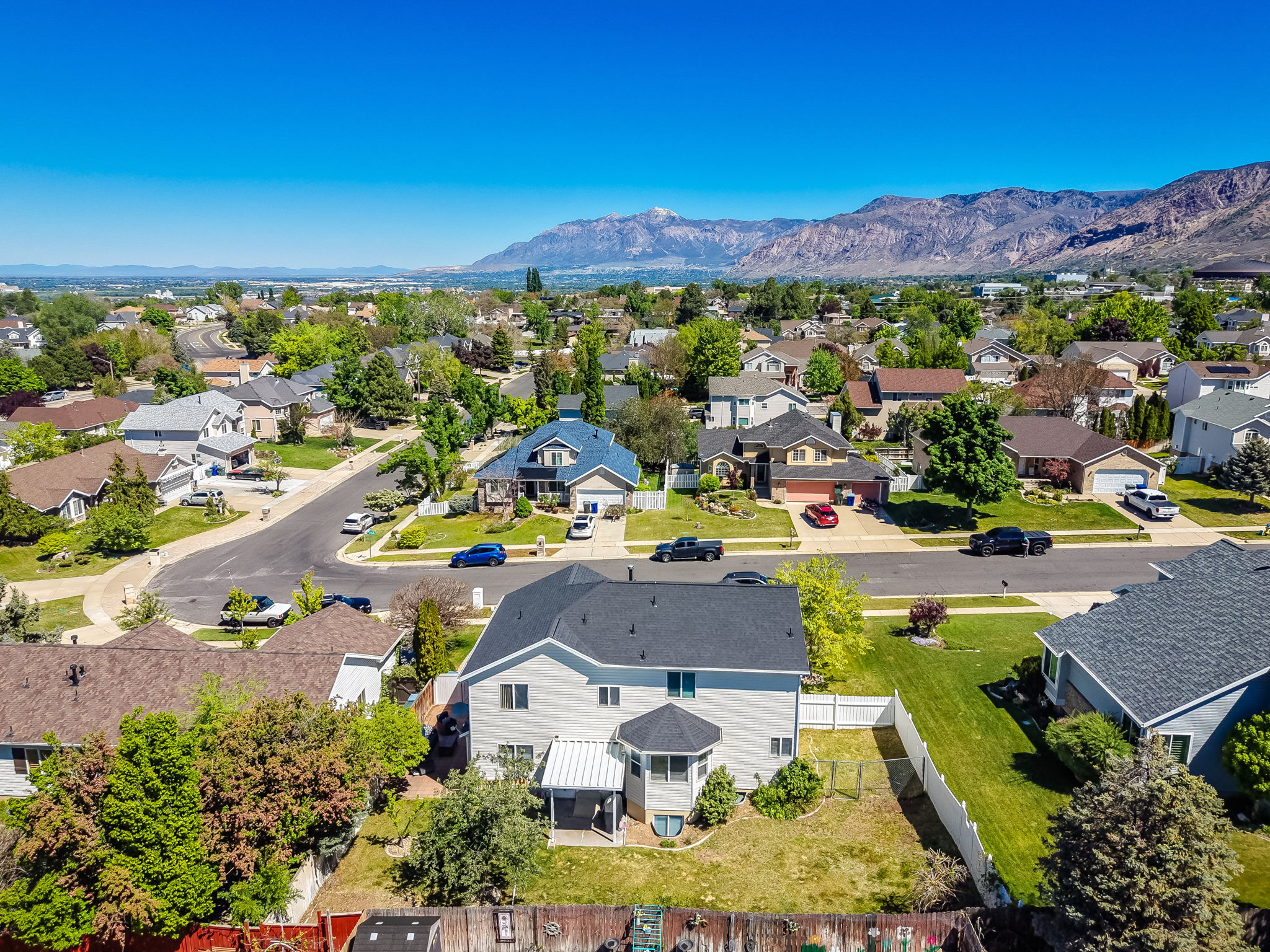 Suburban residential area featuring multiple detached homes with various architectural styles, paved roads, and mature landscaping