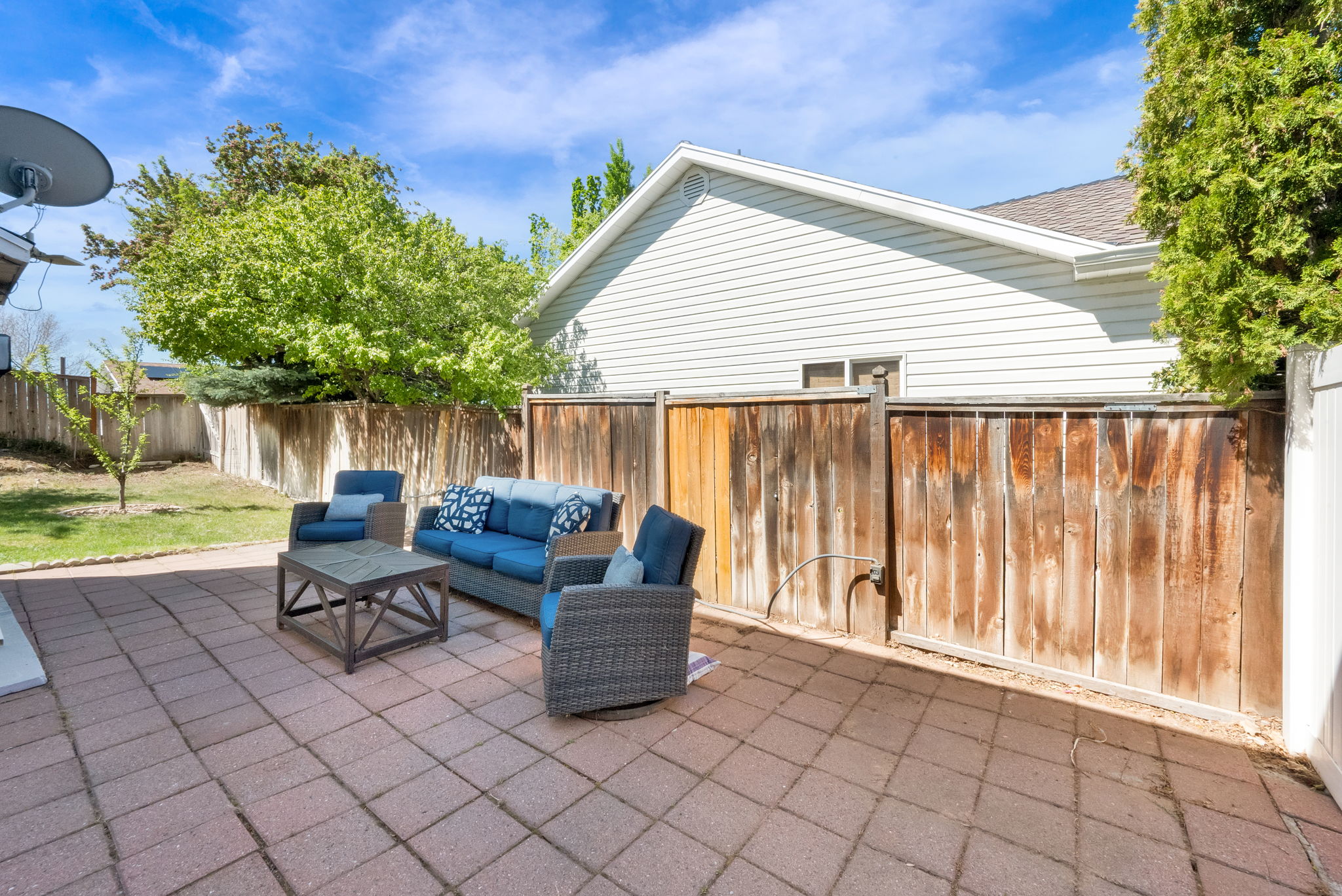 Paver patio with a surrounding wood fence and mature landscaping