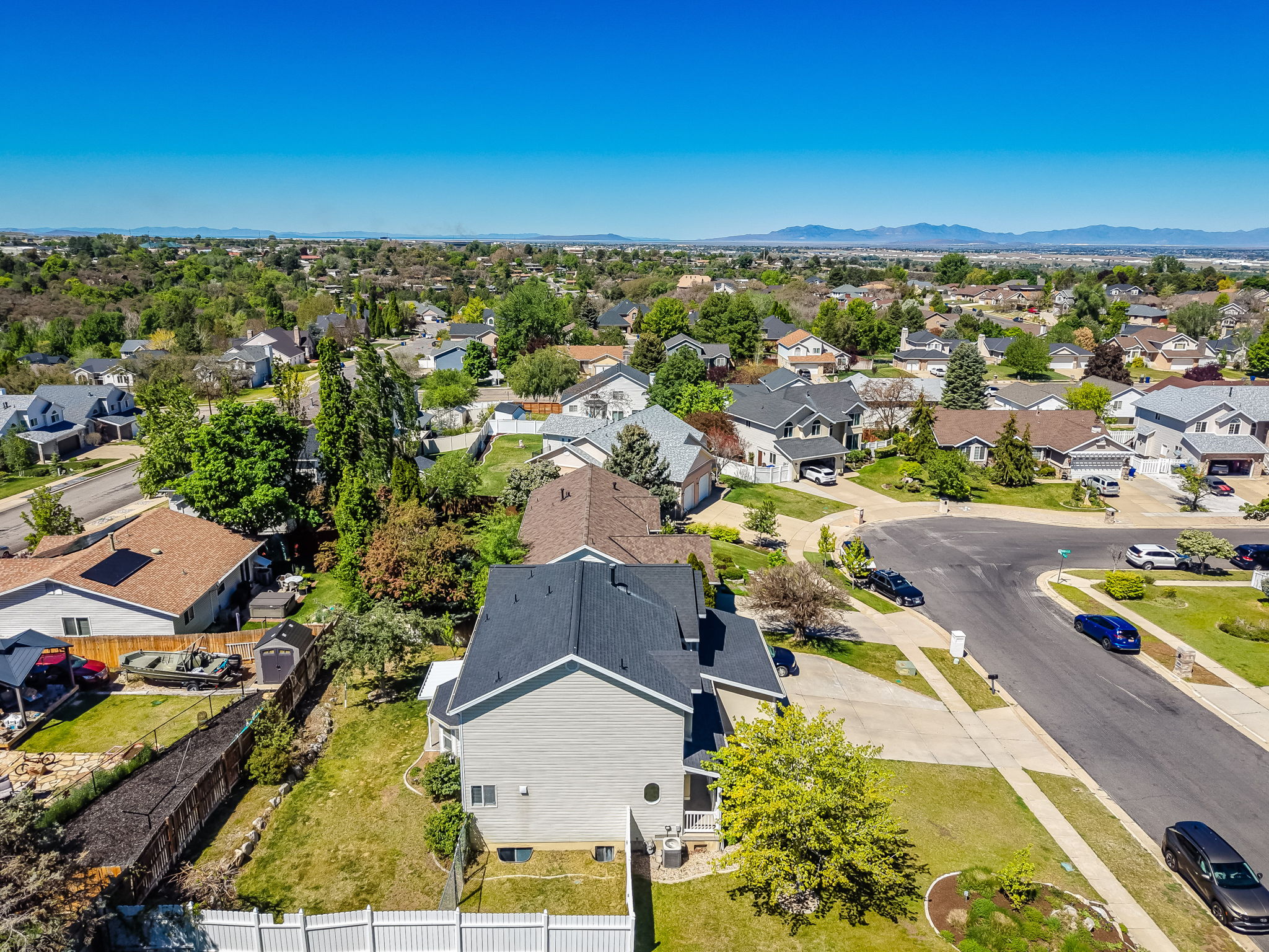Aerial perspective of a residential neighborhood featuring diverse housing styles, mature trees, and paved streets