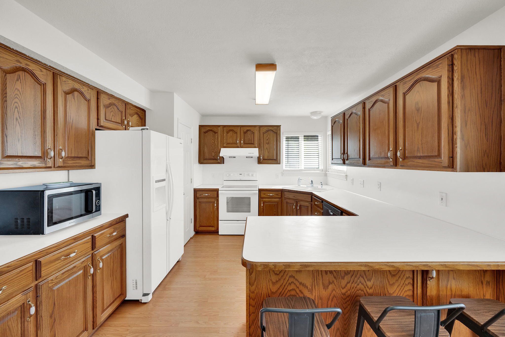 U-shaped kitchen featuring wood cabinetry, white countertops, and wood-finish flooring