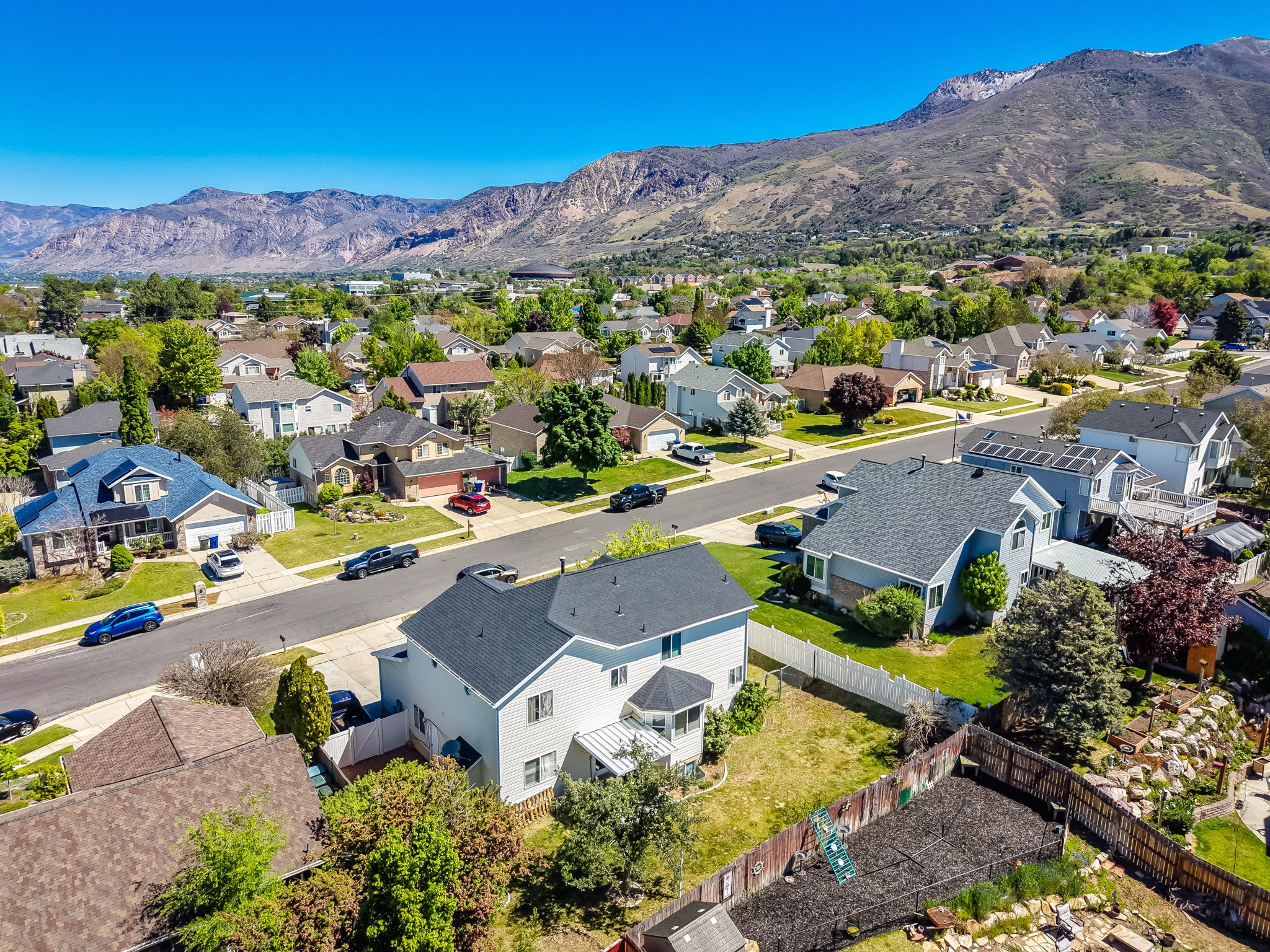 Residential neighborhood with varied architectural styles and mature landscaping framed by distant mountains