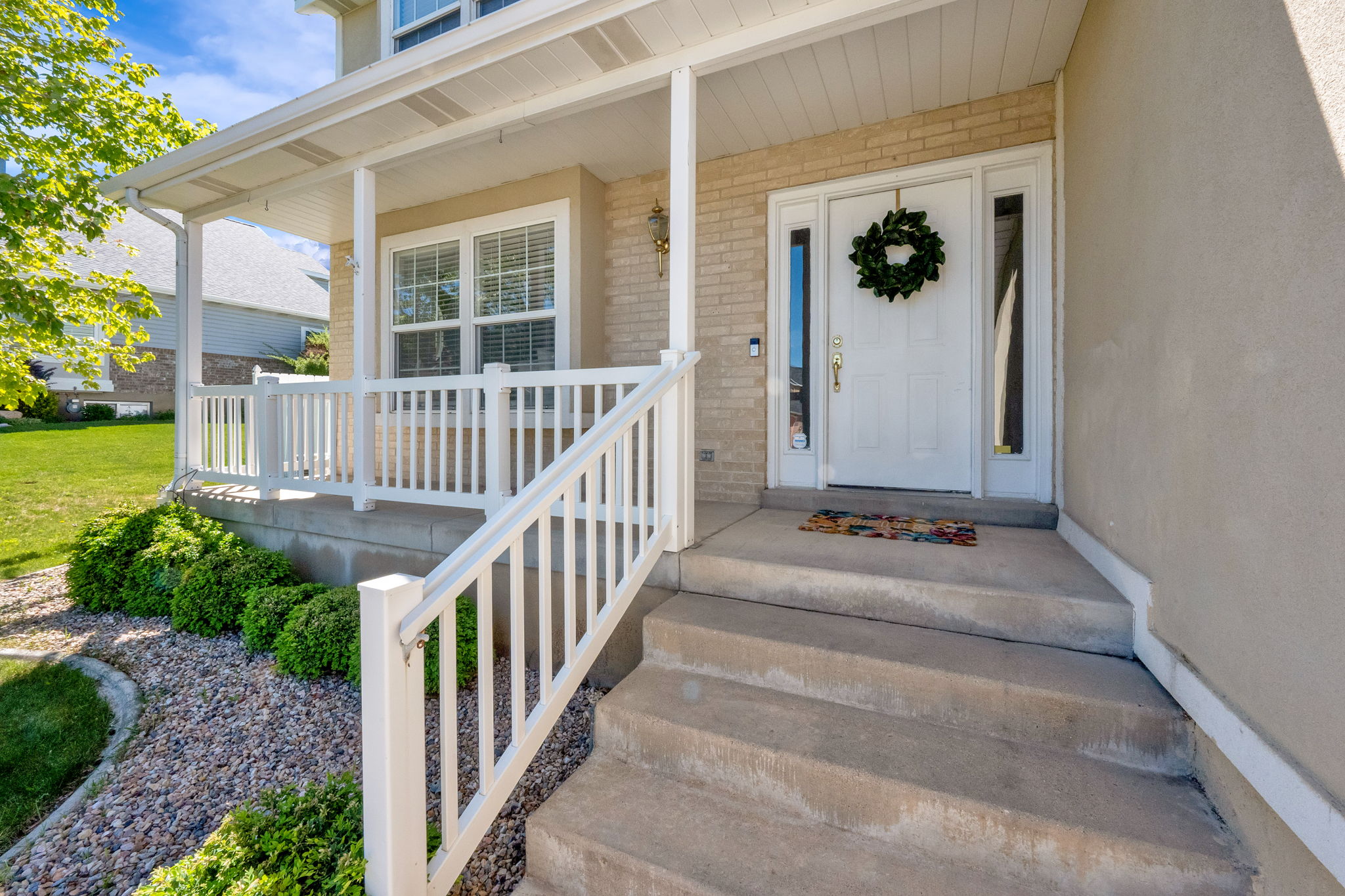 Covered front porch featuring white railings and columns