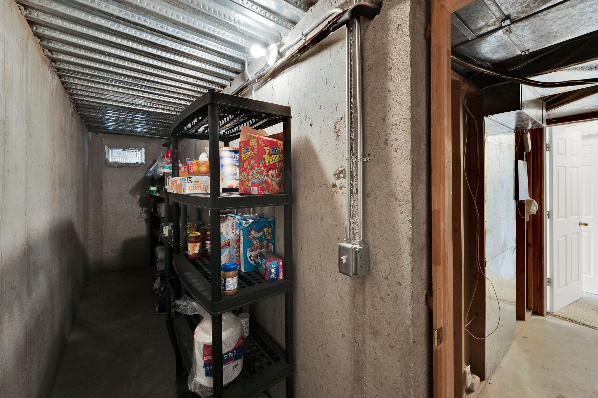 Basement storage area with concrete walls and exposed metal ceiling