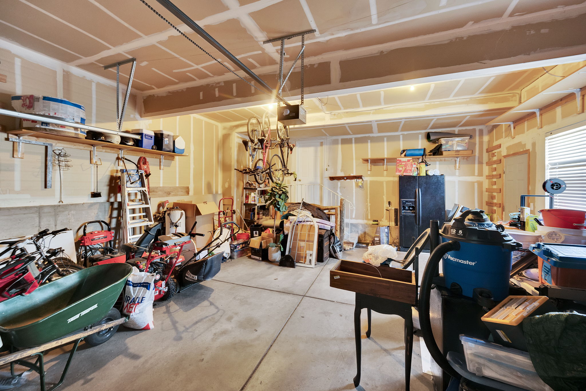 Attached garage featuring a concrete floor, exposed ceiling joists, and a window with blinds