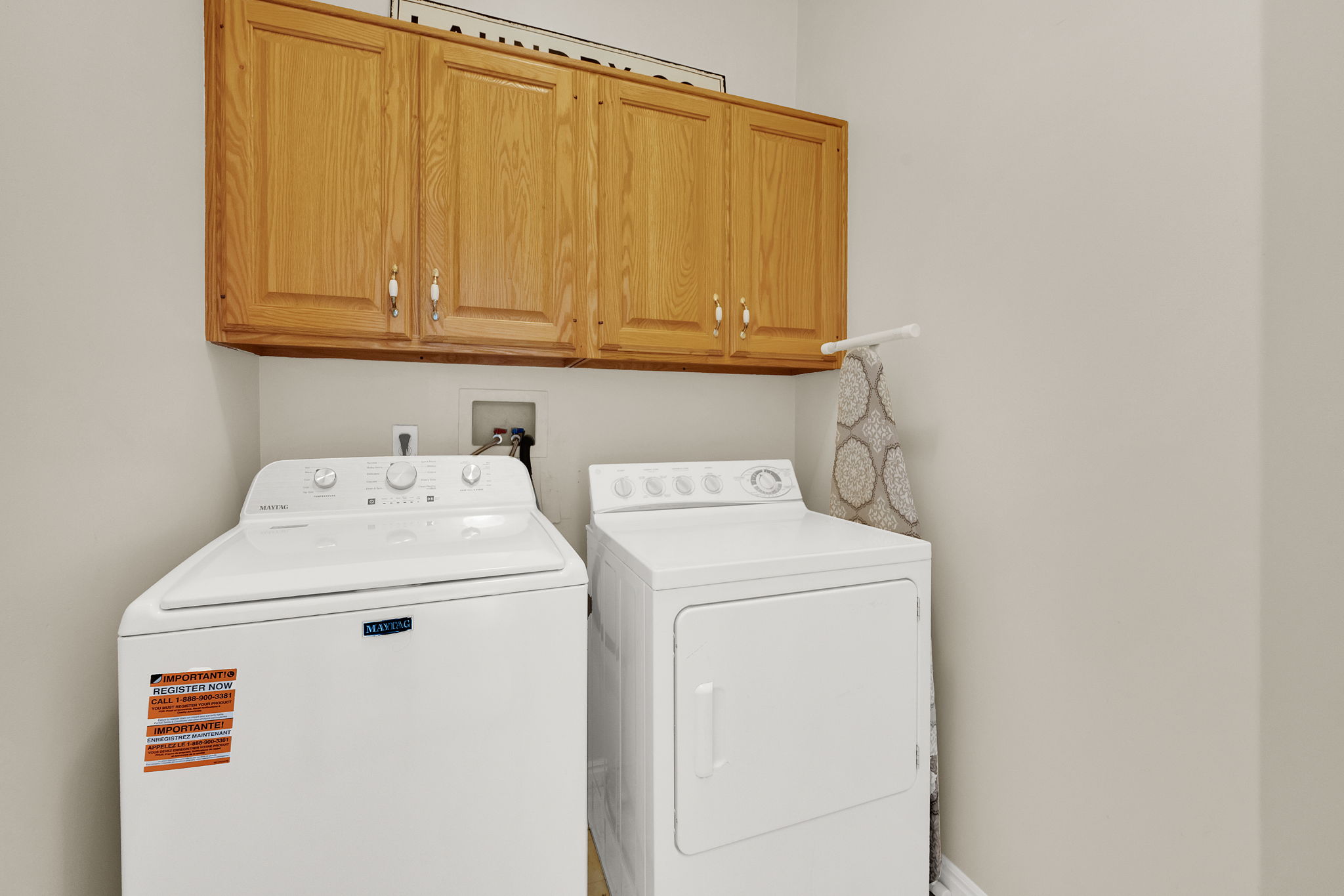Laundry area featuring overhead wood cabinetry with silver-tone hardware, providing practical storage solutions