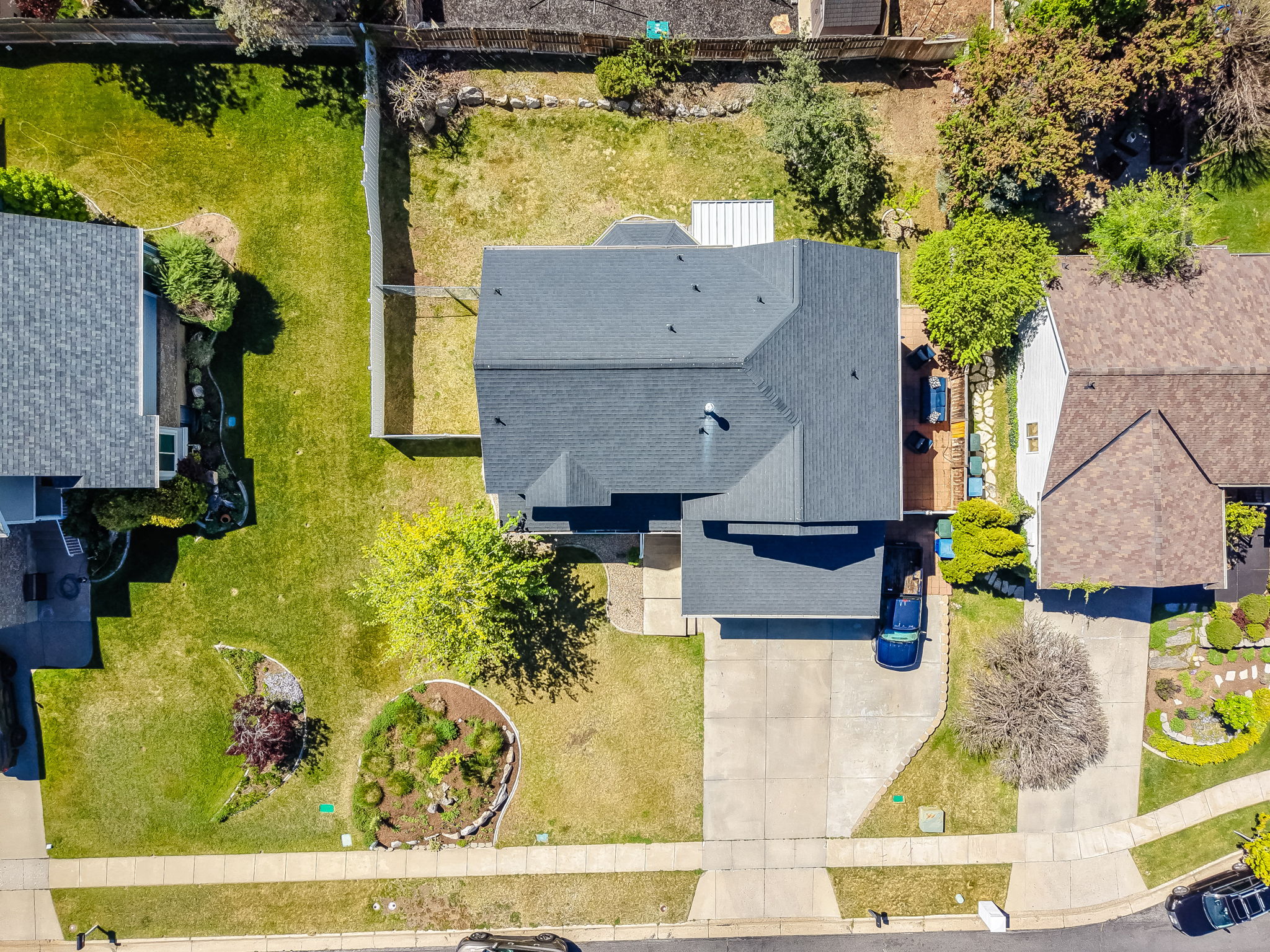 Residential property featuring a dark-toned roof, concrete driveway, and a front yard with landscaped beds