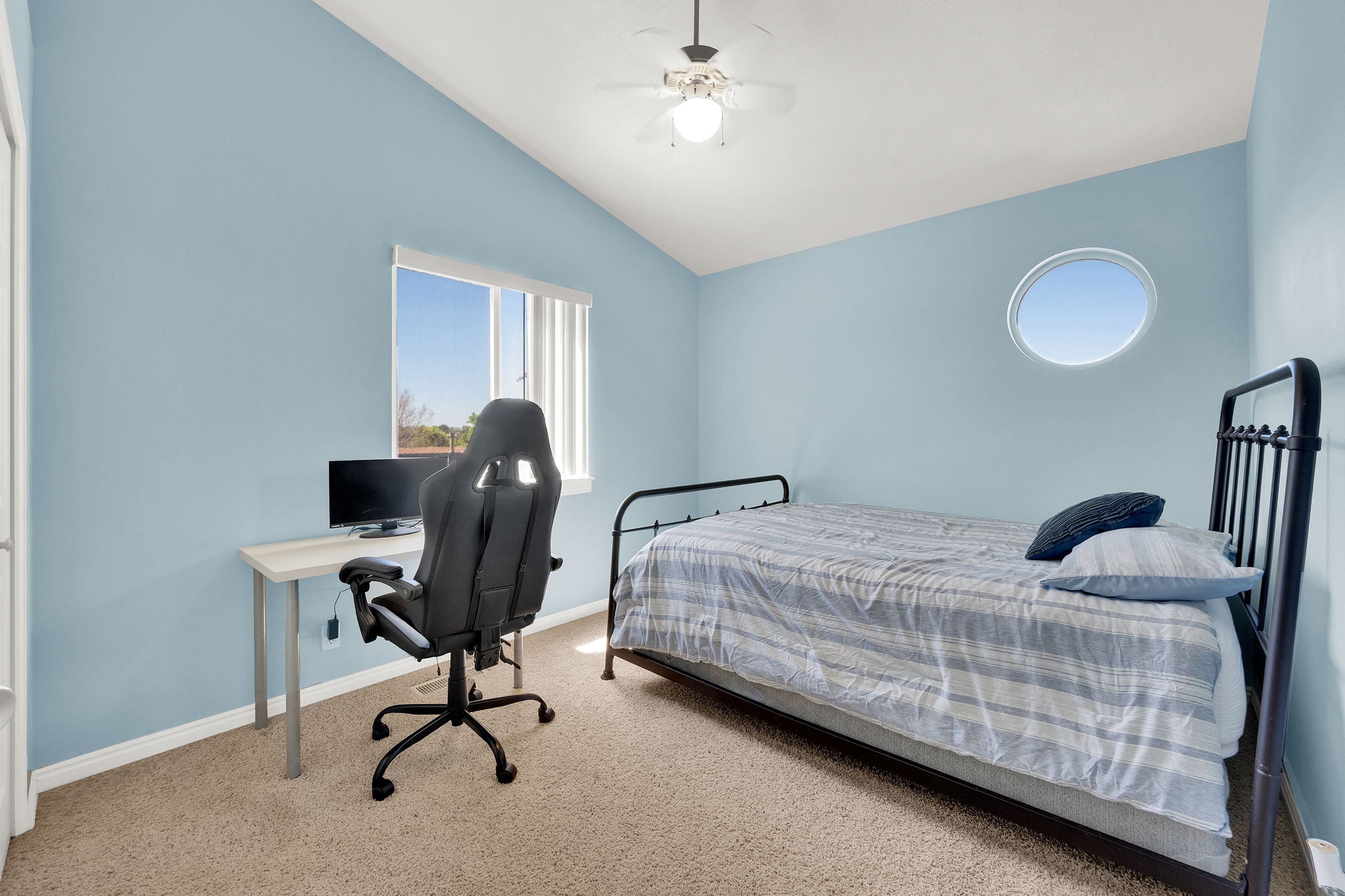 Room featuring an architectural vaulted ceiling, round accent window, and ceiling fan with integrated lighting