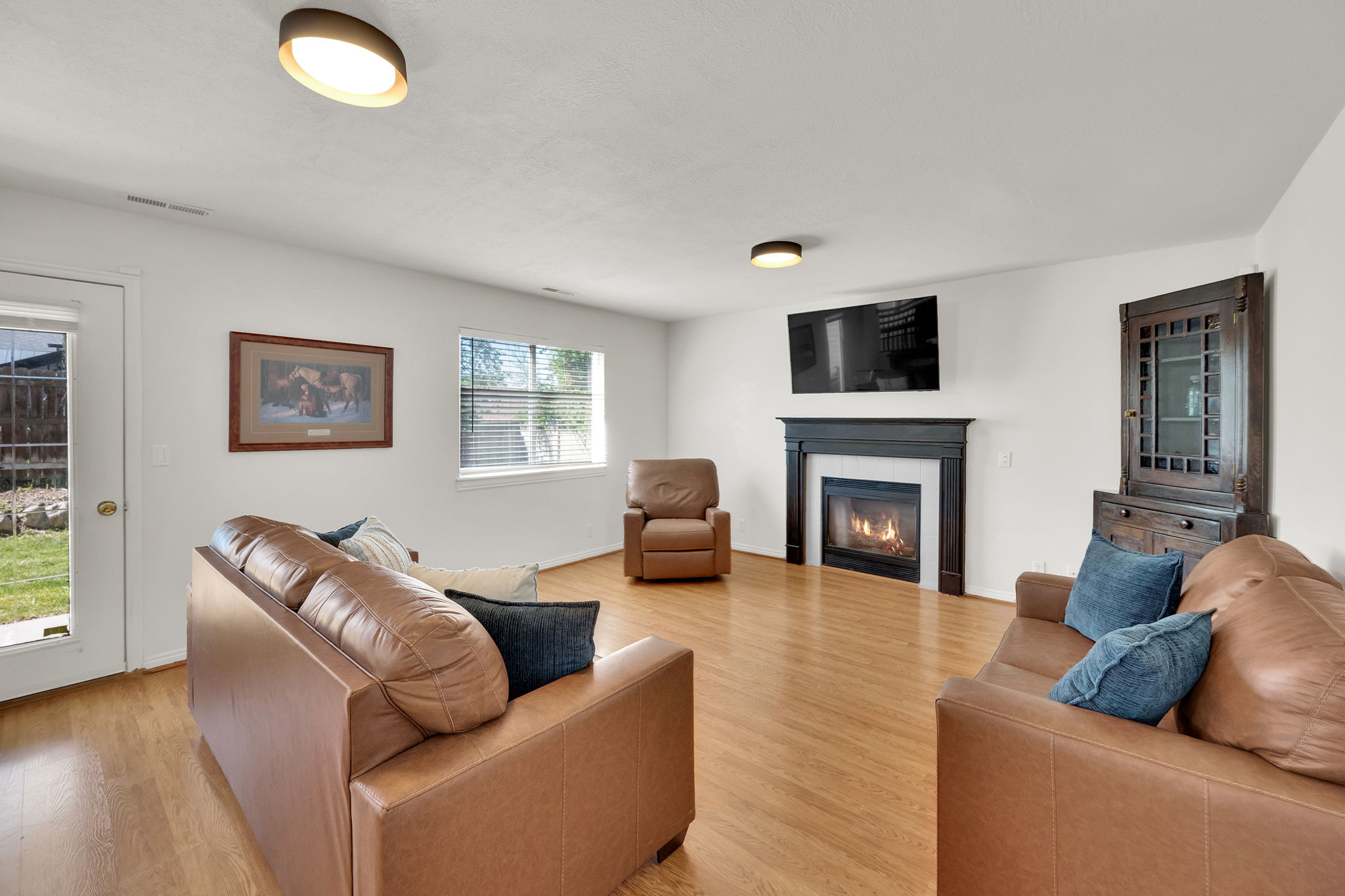 Living area featuring wood-finish flooring, a white ceiling with flush-mount lighting, and a fireplace with a dark-stained wood mantel